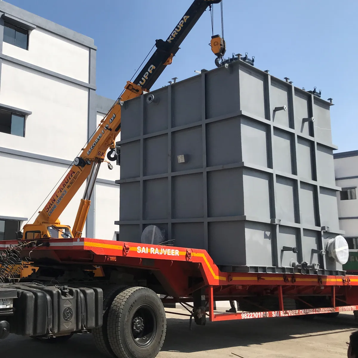 Rectangular hot well tank being lifted onto a trailer